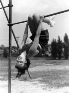 h-armstrong-roberts-smiling-teen-girl-on-playground-hanging-upside-down-on-monkey-bars
